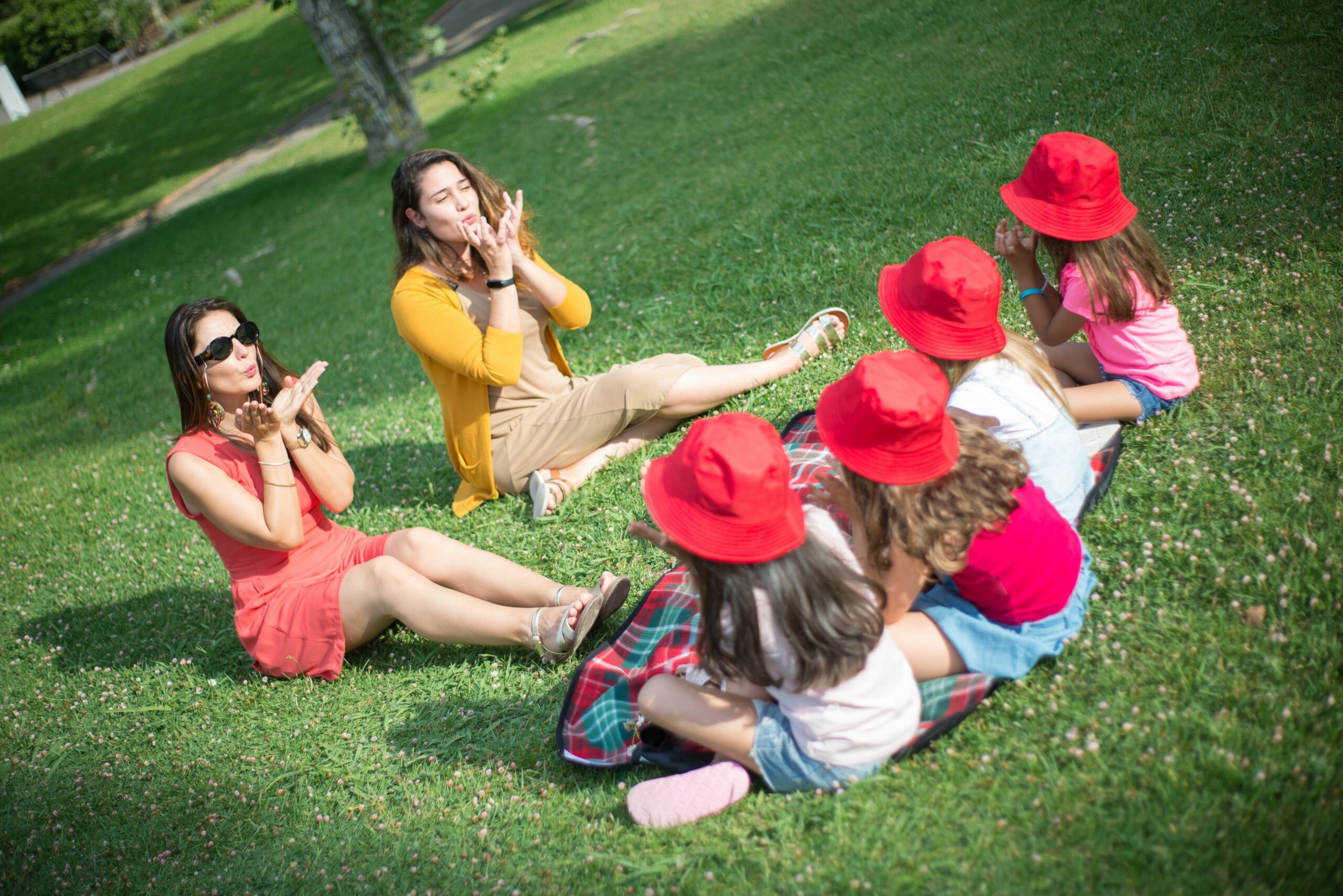 Two adults and children playing together on grass in a sunny Portuguese park.